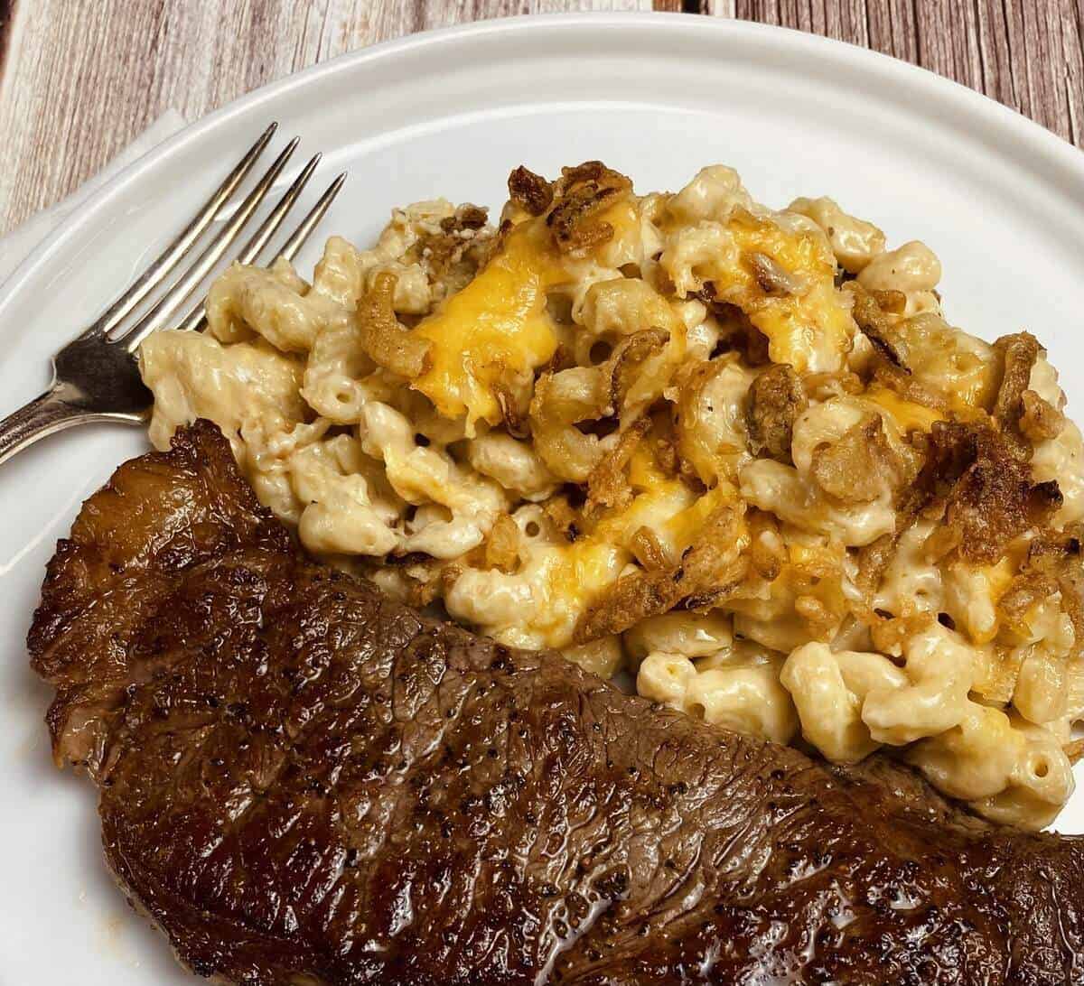 Plate of guinness mac & cheese with a steak and a fork.