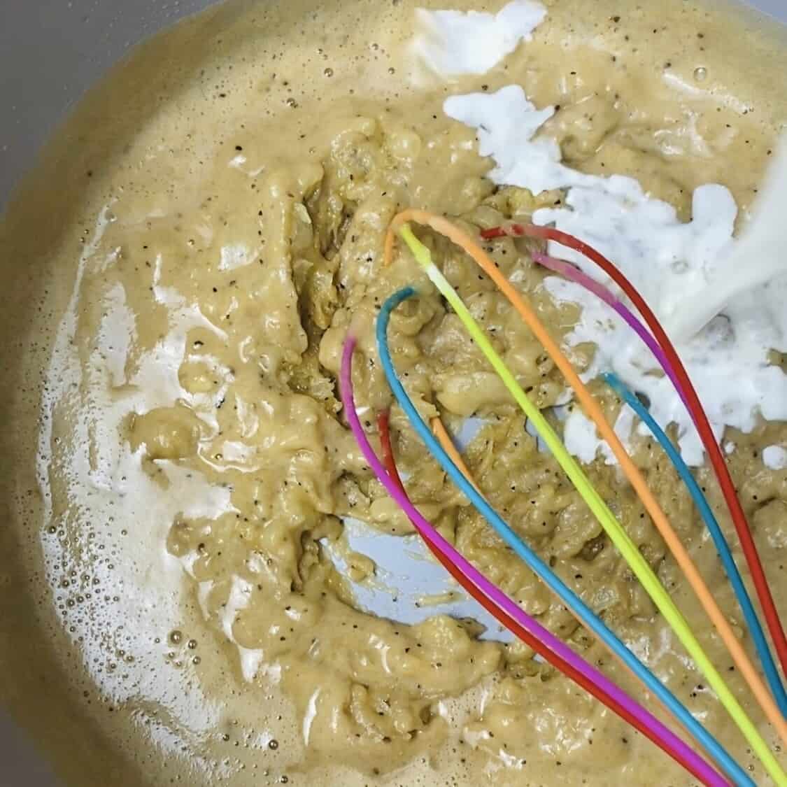 A whisk stirring milk and guinness beer into the roux.