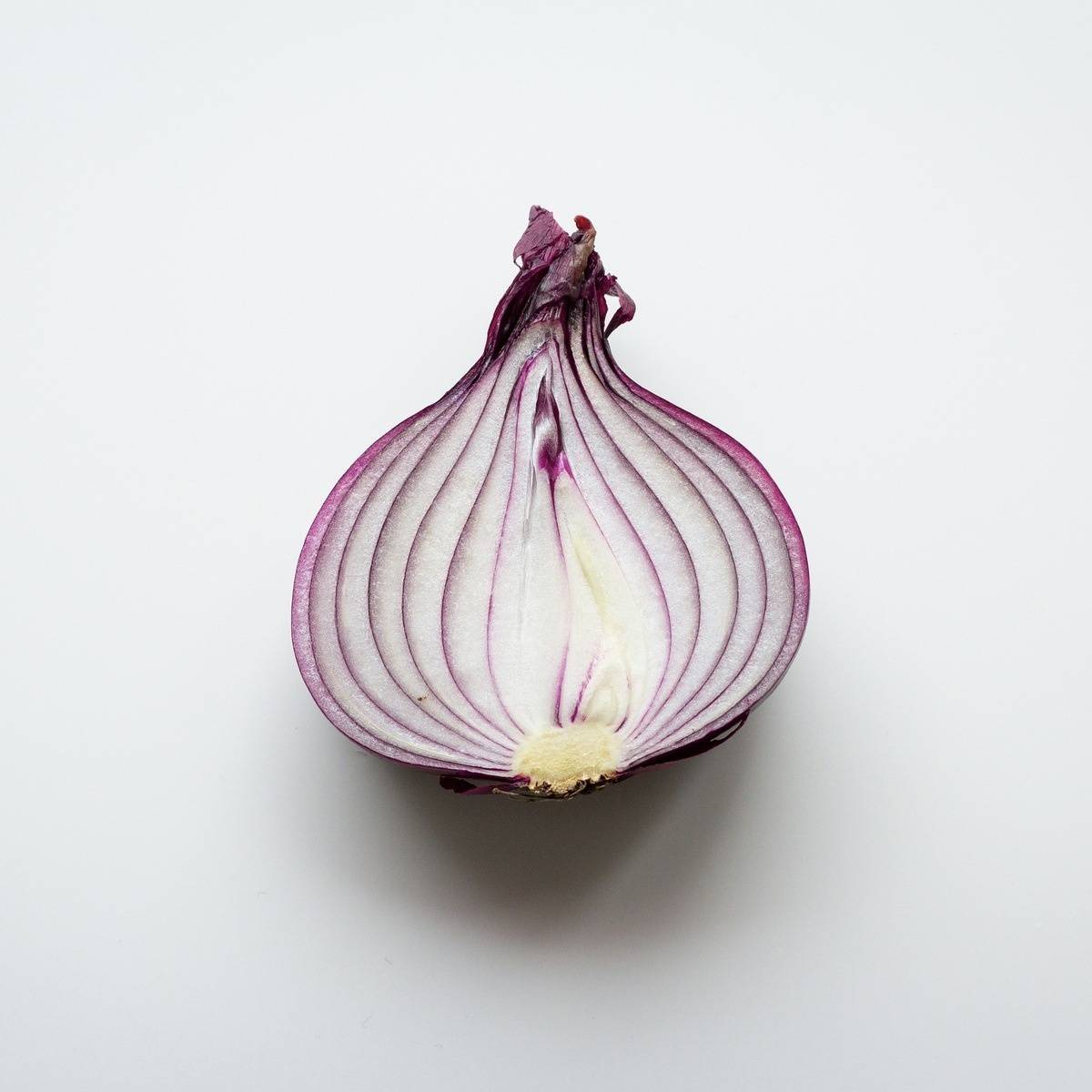 A red onion sliced down the middle and exposing the layers.