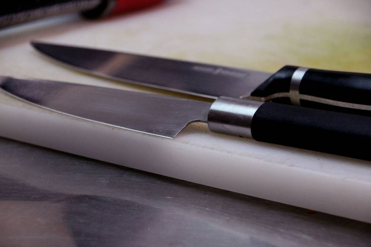 Two chef's knives on a cutting board.