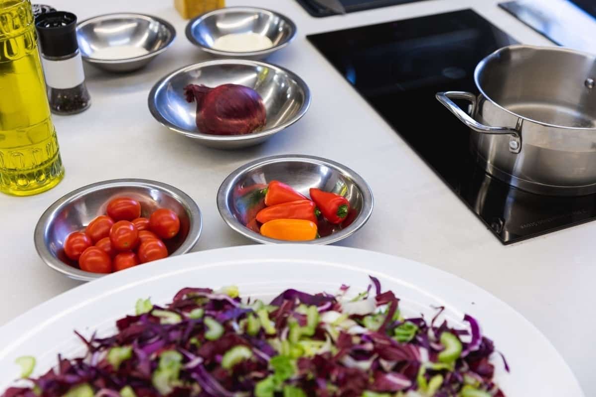 Several bowls on a kitchen counter near a stovetop filled with mise en place prepped food.