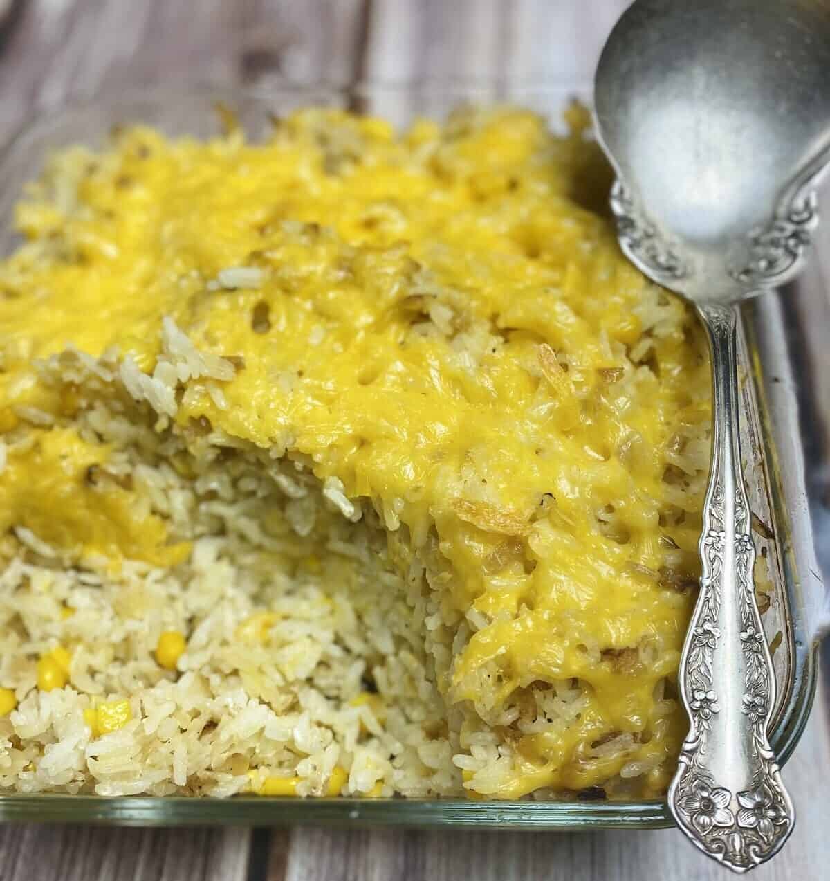 A baking dish of baked sour cream rice and a serving spoon.