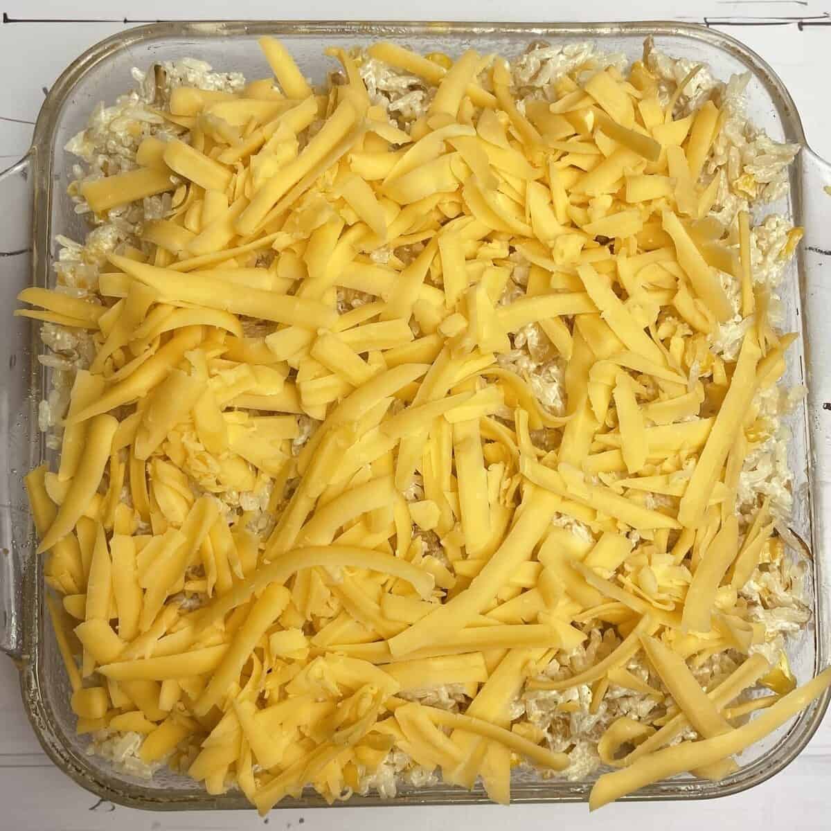 A baking dish with the rice mixture topped with shredded cheese.