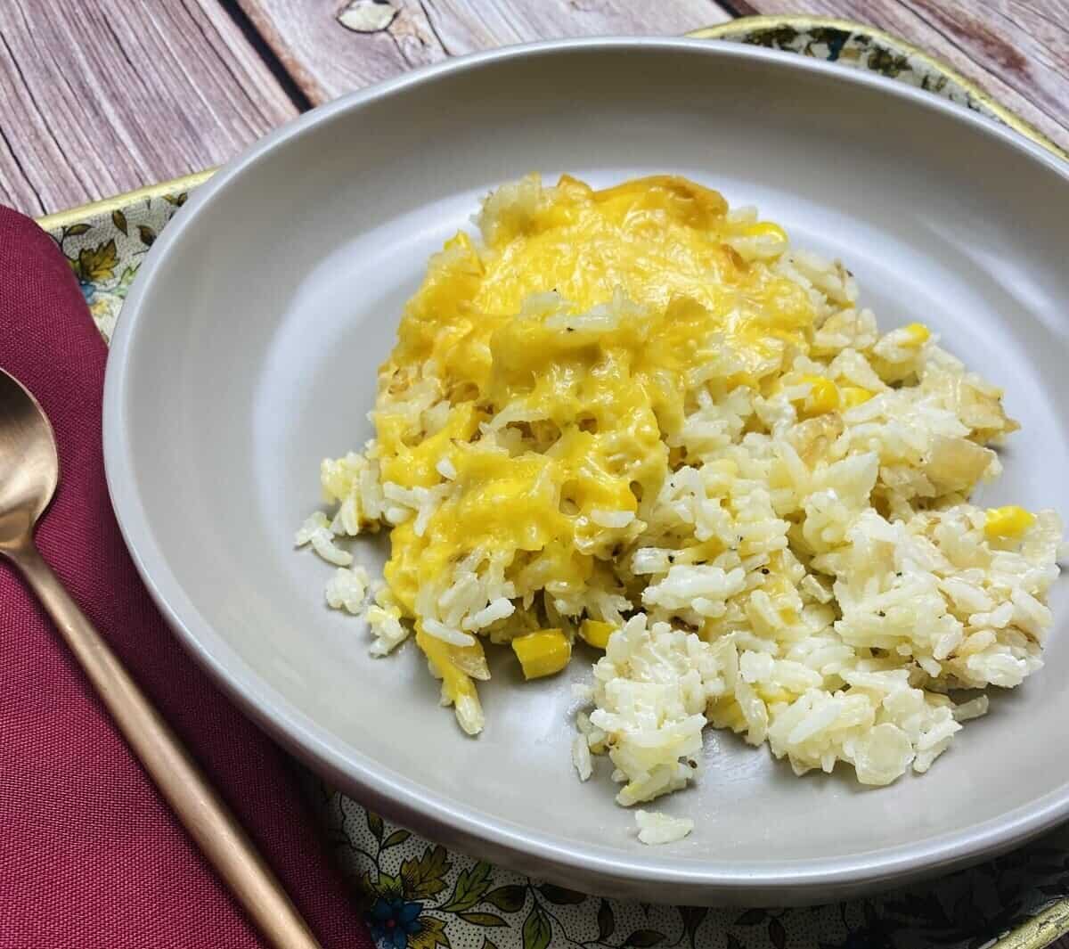 A serving of the rice casserole on a plate alongside a spoon and napkin.