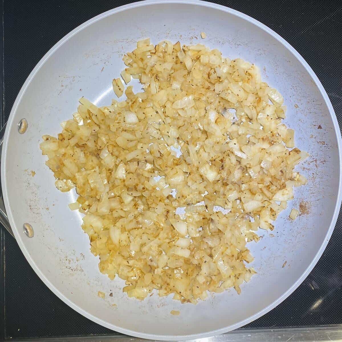 A saute pan with cooked diced onions.