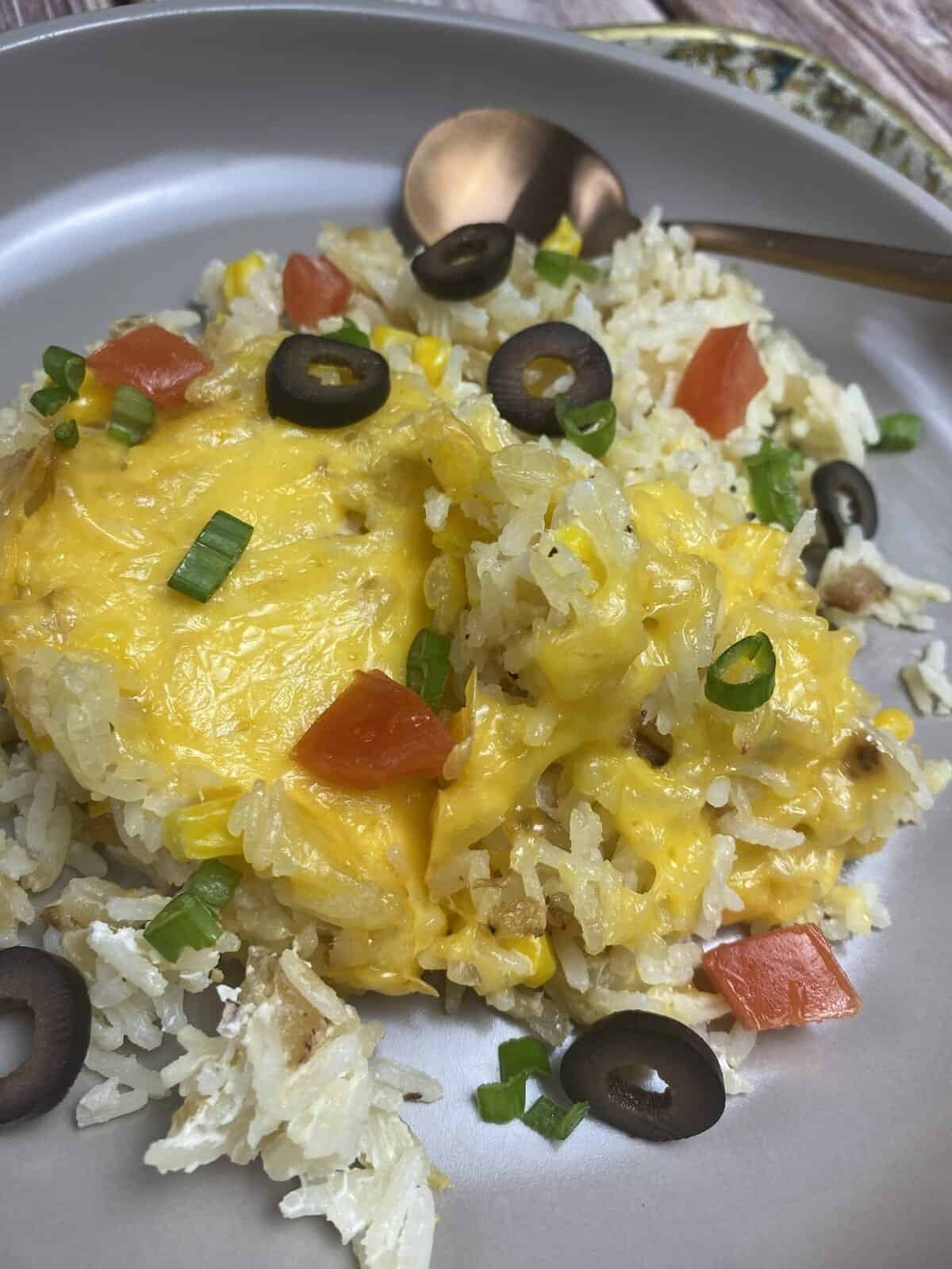 Sour cream rice with extra toppings in a dish with a spoon.