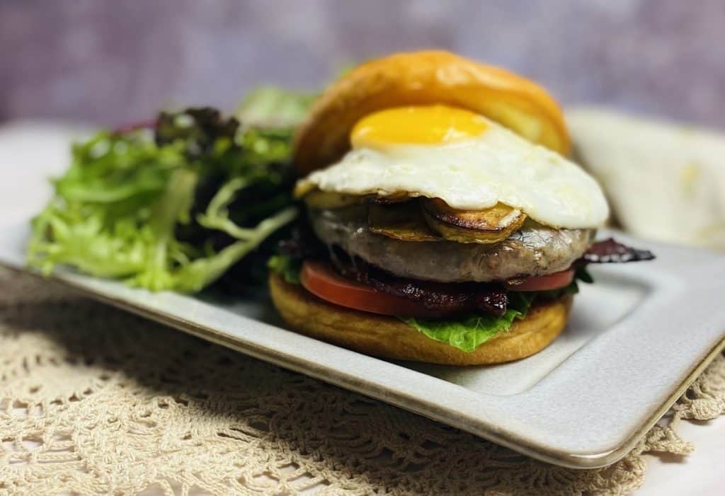 A brunch burger on a plate with a green salad.