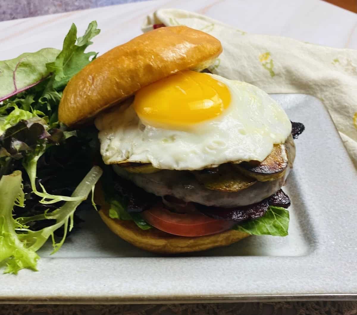 A brunch burger with a runny egg and a salad.