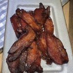 A plate filled with maple bacon and a napkin.