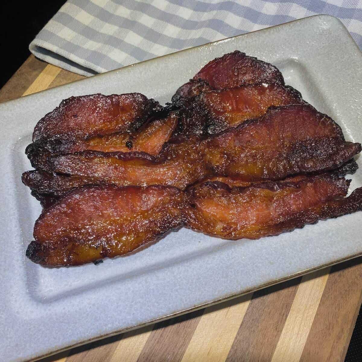 A plate and napkin with cooked bacon slices.