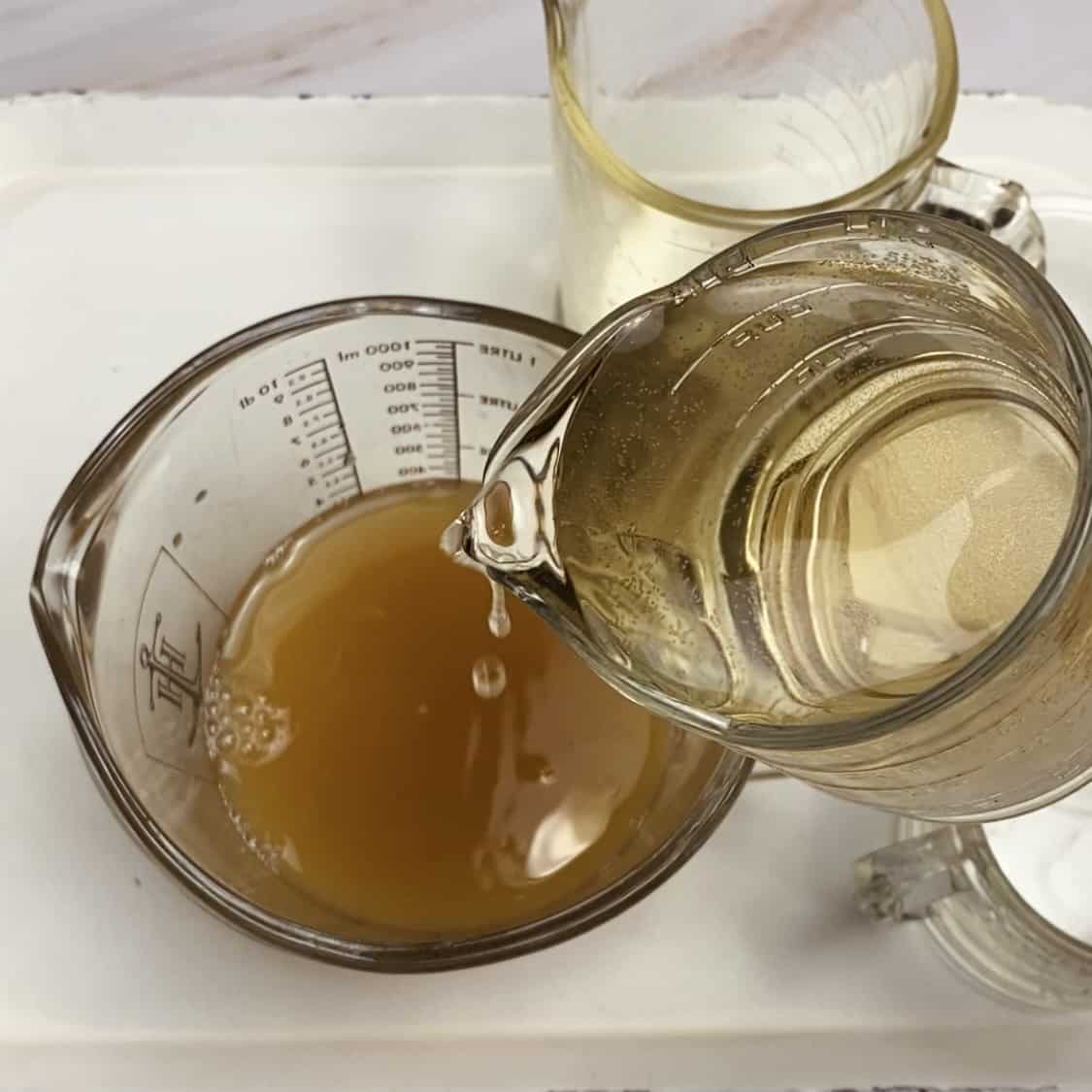 A pitcher of wine being poured into a pitcher of juice.