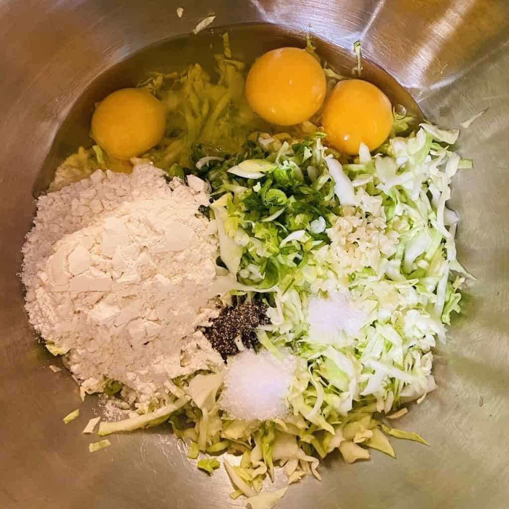 All the ingredients to make cabbage fritters in a bowl.