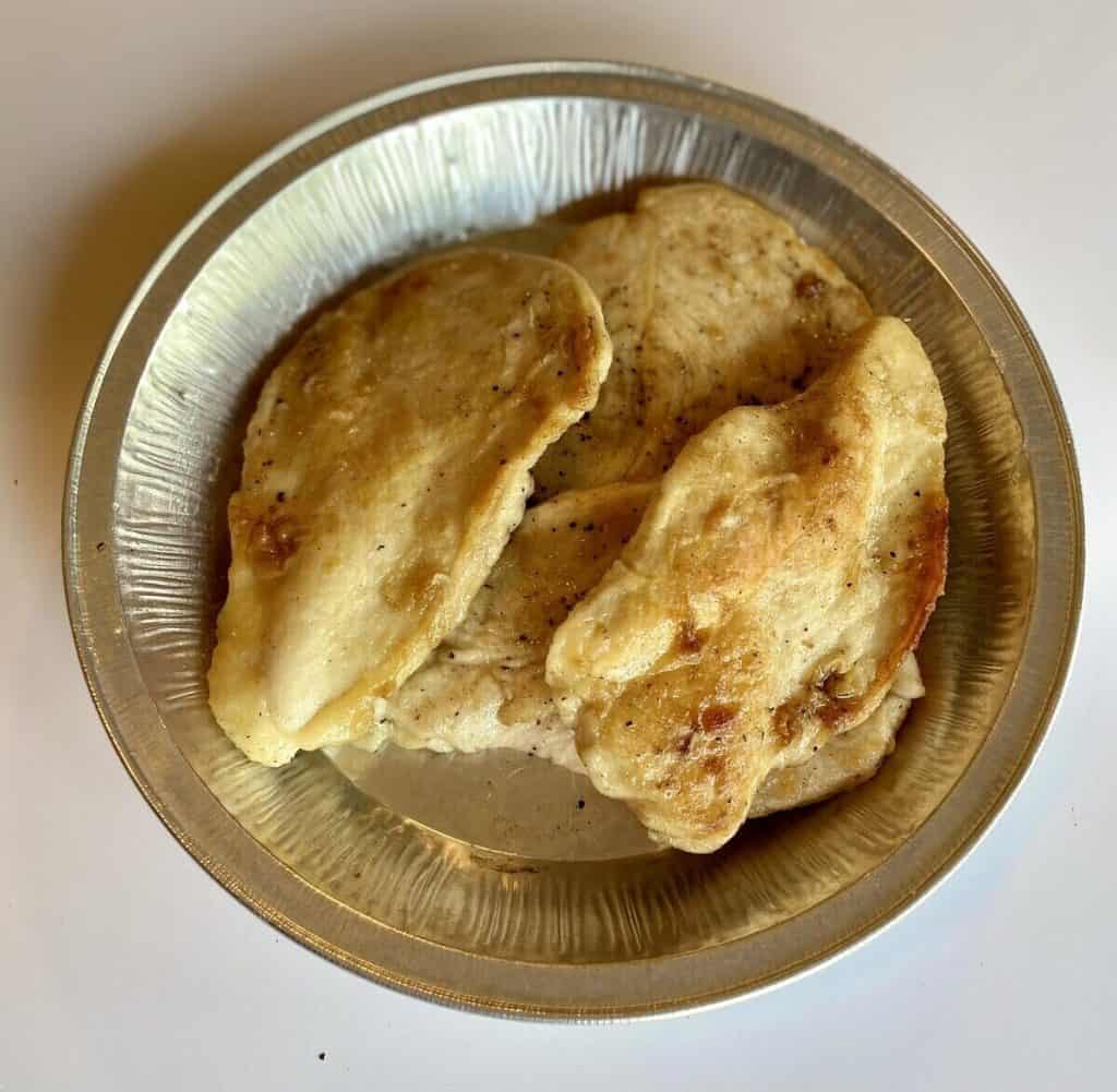 A tray holding cooked chicken breasts.