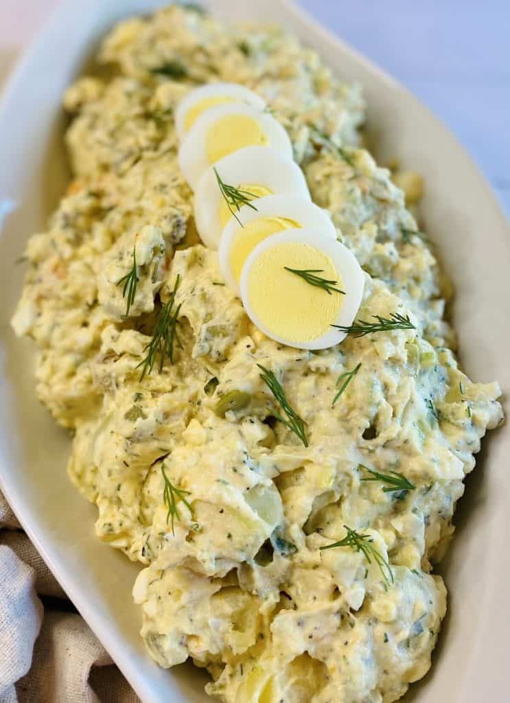 Sliced eggs on top of a bowl of tater salad.