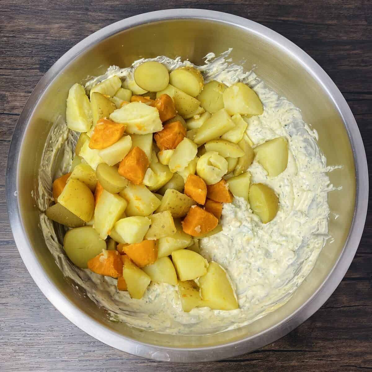 Potatoes, yams, and sweet potatoes in a bowl with potato salad dressing.