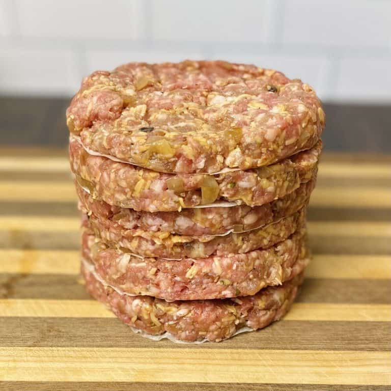 A stack of hamburger patties on a cutting board.