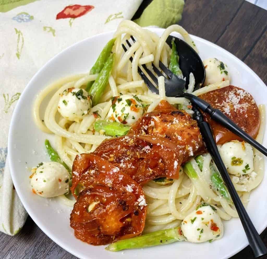 A fork and spoon on top of a bowl of pasta.