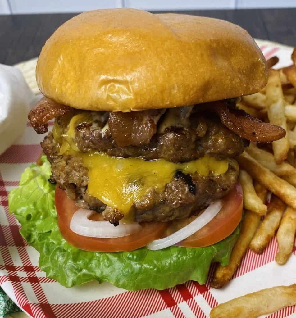 A double patty cheeseburger on a plate with fries.