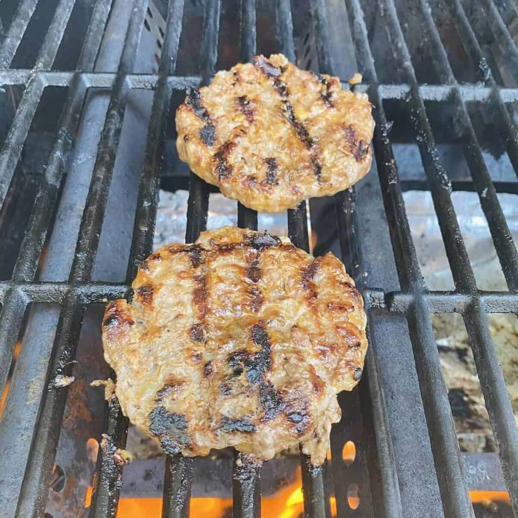 Two cooked burger patties on a bbq grill.