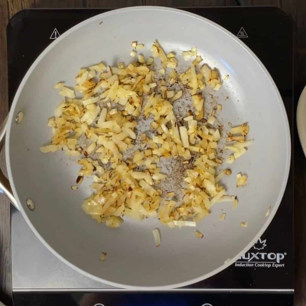 A fry pan with cooked onions.