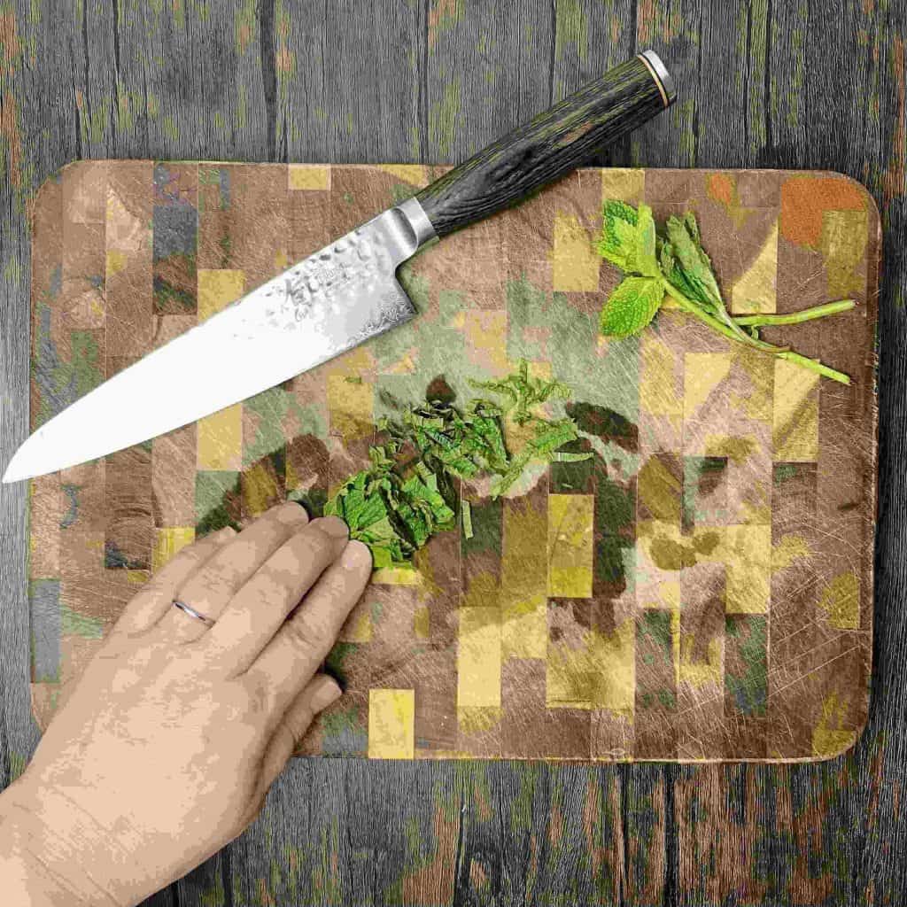 Sliced mint on a cutting board with a knife