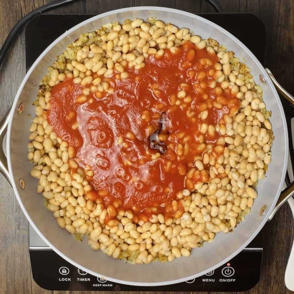 A skillet with beans, tomato sauce and soy sauce added.