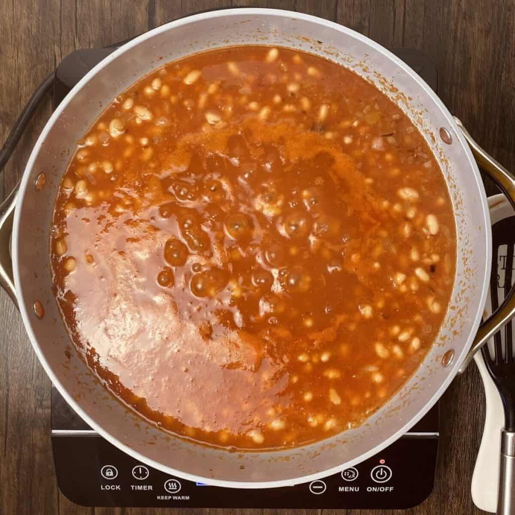 A skillet simmering tomato and bean soup.