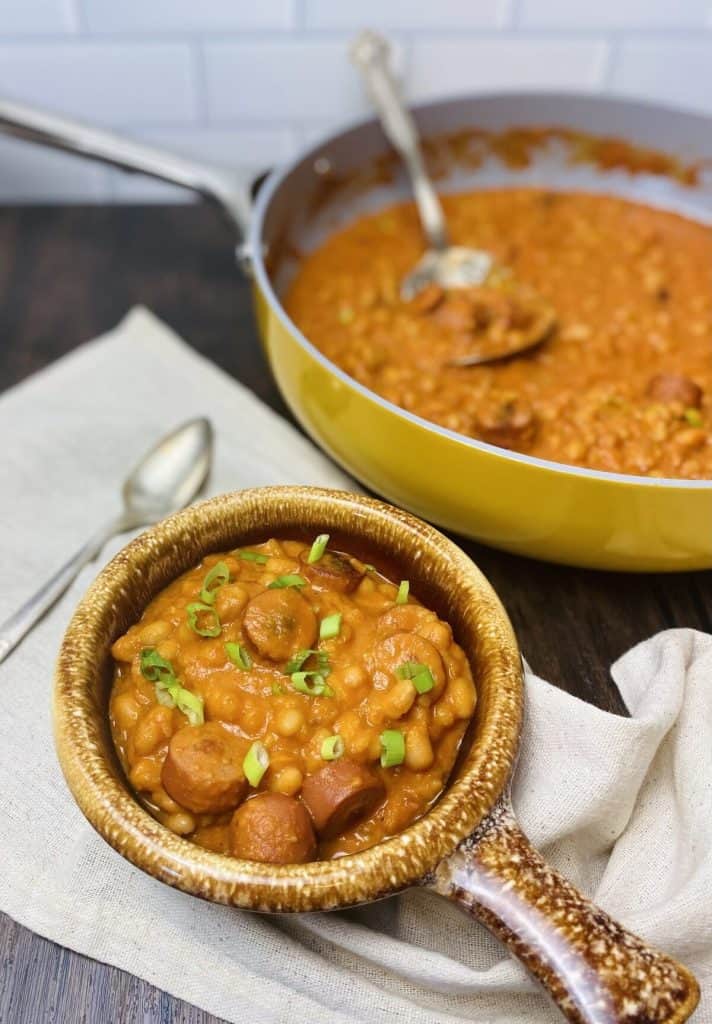 A bowl of soup with a skillet of soup in the background.