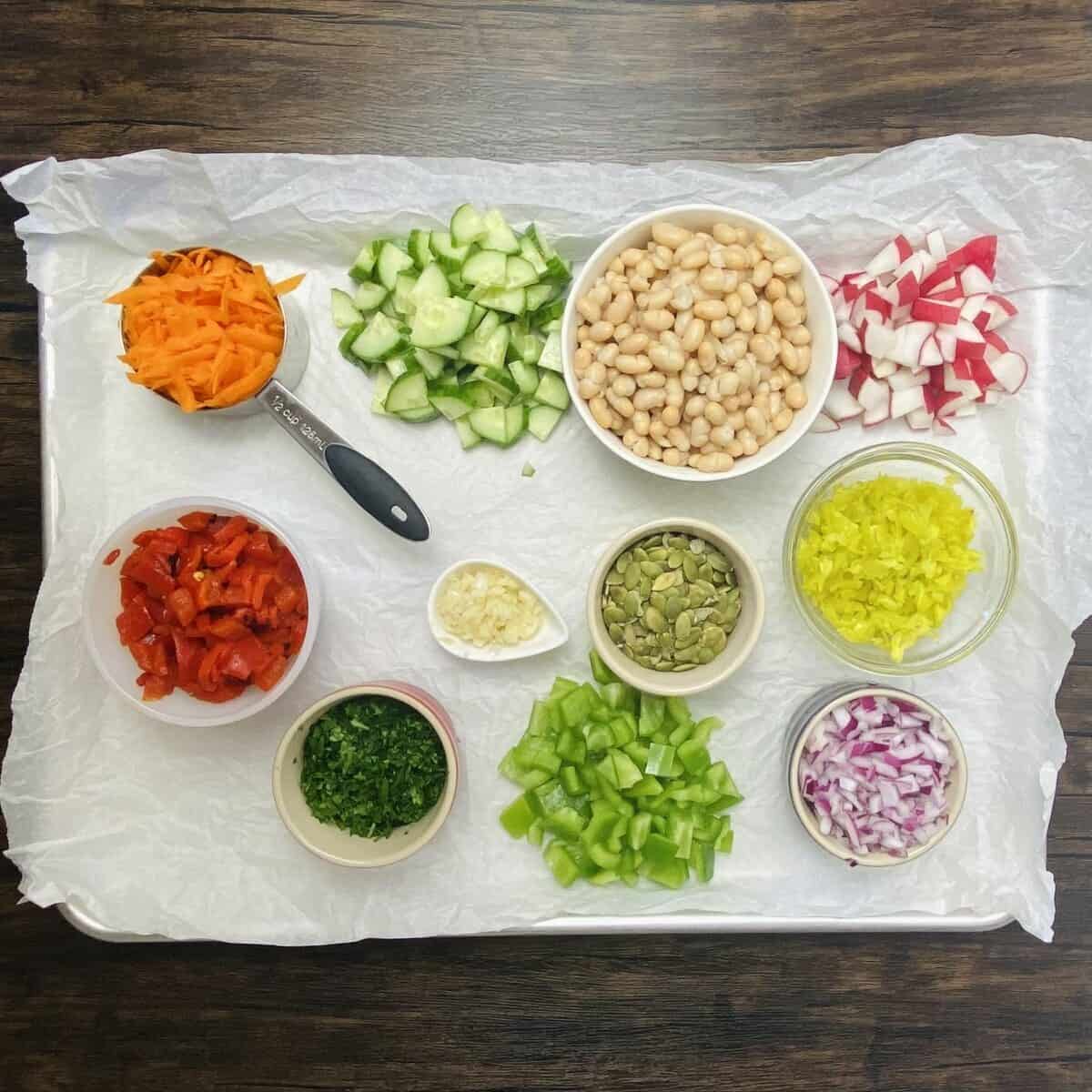 All the ingredients for chopped vegan salad prepared and set out on parchment paper.