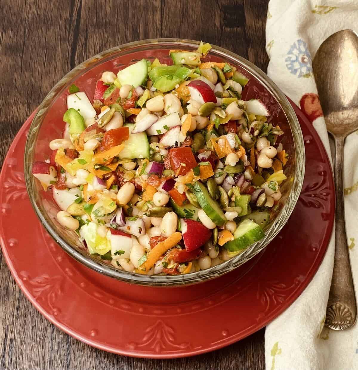 Bowl of chopped vegan salad on a plate with a spoon.