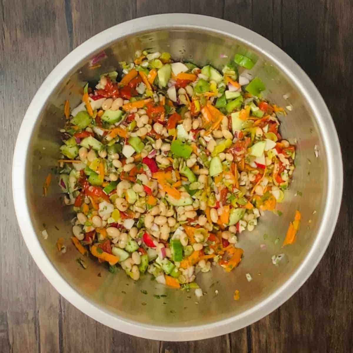 All the salad ingredients mixed up in a large metal bowl.