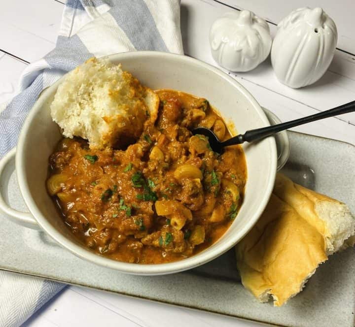 American beef goulash in a bowl with a side of crusty bread.