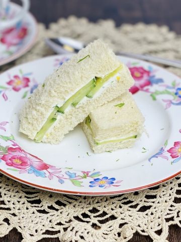 Two cucumber finger sandwiches on a china plate.