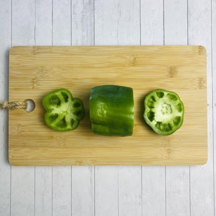 A bell pepper on a cutting board with the ends removed.