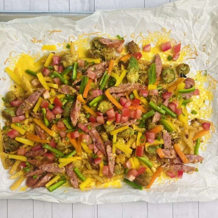 Dirty fries on a sheet pan with fresh vegetables on top.