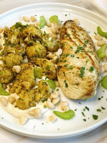 Plate of chicken with cauliflower and bean hummus.