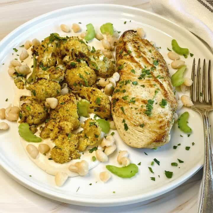 Plate of chicken with cauliflower and bean hummus.