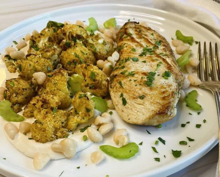 Chicken, hummus, and cauliflower on a plate with a fork.