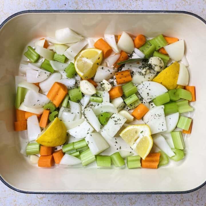 The roasting dish filled with vegetables and herbs.