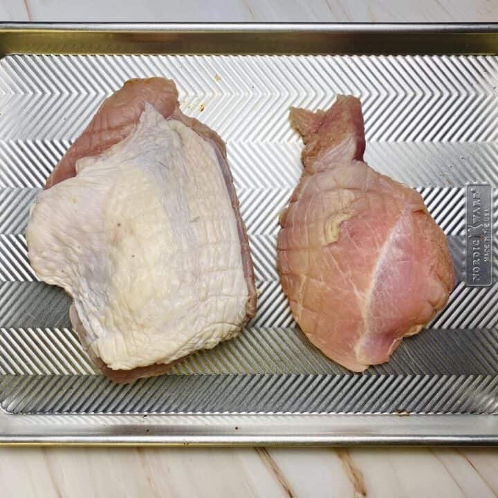 The raw turkey breast pieces separated onto a sheet pan.