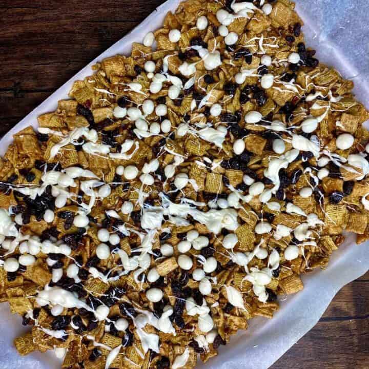 Crunch mix on a sheet pan with added raisins and melted candy drizzle.