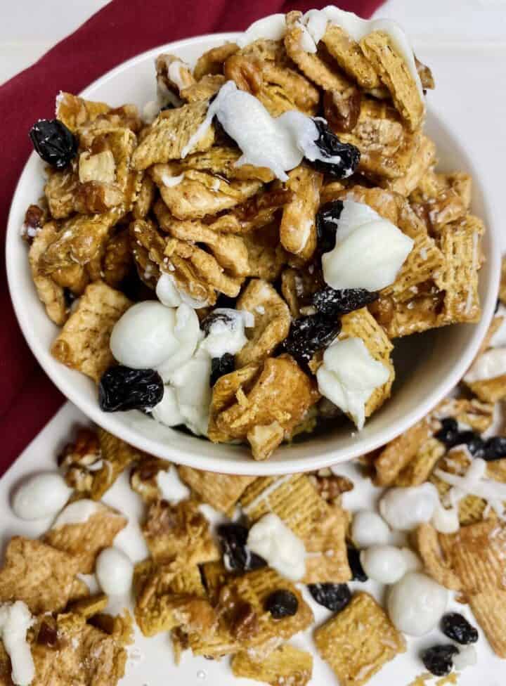 A bowl holding a handful of cinnamon roll crunch mix.