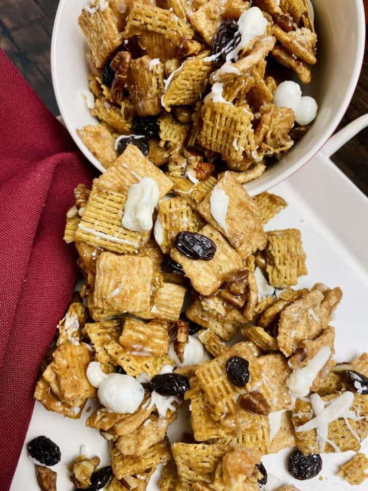 A bowl dumping crunch mix onto a tray with a napkin.