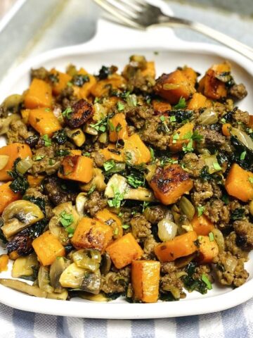 A white plate with a serving of hash alongside a fork.