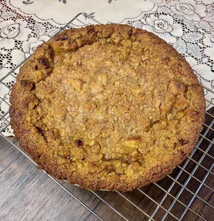 A whole finished cardamom apple pie on a cooling rack.