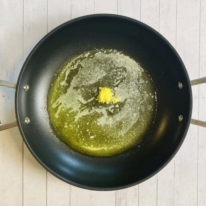 A skillet sauteing fresh ginger in butter.