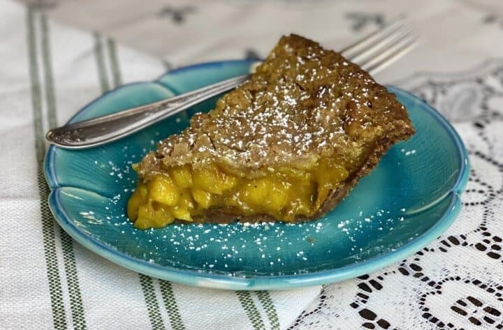 A slice of cardamom apple pie on a blue plate with a fork.