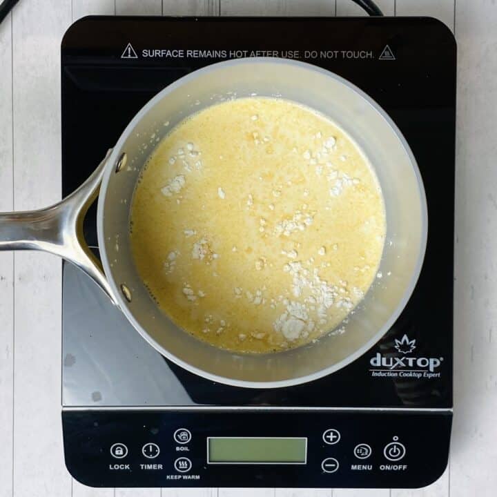 A pot filled with cheese sauce ingredients on a burner.