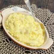 A dish of rustic mashed potatoes with a serving spoon.