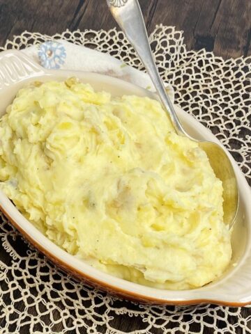 A dish of rustic mashed potatoes with a serving spoon.